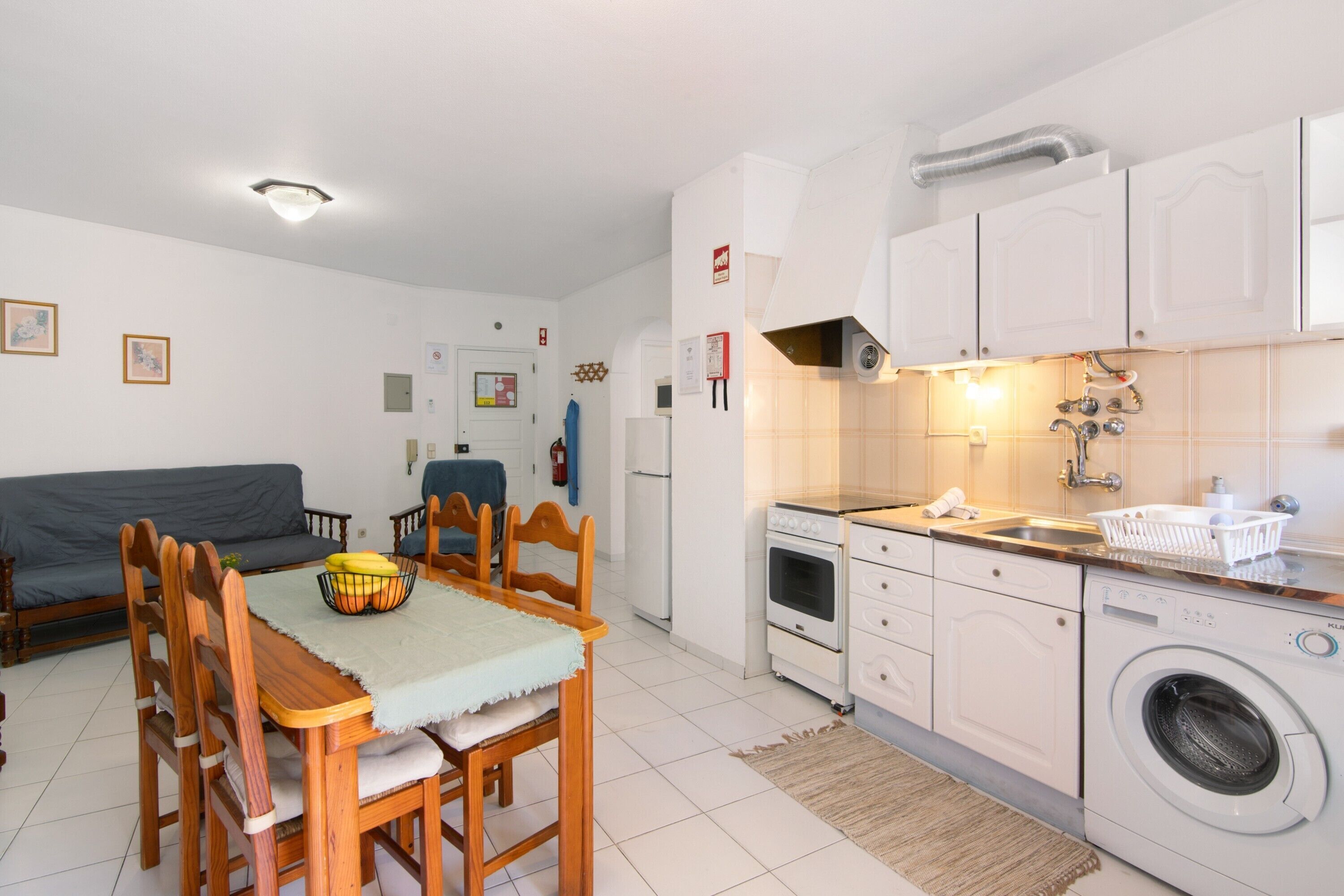 Cocina compacta con comedor, lavadora y sofá.