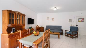 Un comedor con muebles de madera, televisor y sofá.
