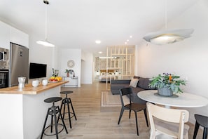 Une cuisine moderne dotée d’un plan de travail en bois, de tabourets de bar et d’un four encastré.