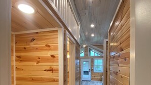 A hallway with wooden paneling and a black trash bin. - Rustic Tiny Home Escape - Pets Stay Free! (Georgetown)