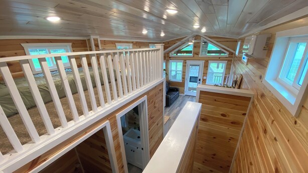 A cabin interior with a loft bedroom, a staircase, and a kitchen area. - Rustic Tiny Home Escape - Pets Stay Free! (Georgetown)
