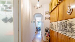 Un pasillo con suelo de madera, un candelabro, cuadros enmarcados y un aparador con obras de arte.