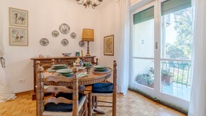 Comedor con mesa de madera, sillas, un candelabro y vistas al exterior a través de amplios ventanales.