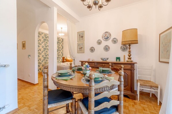 A dining area with a round wooden table, chairs, and a chandelier.