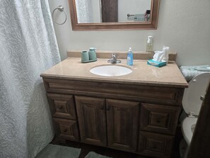 A bathroom with a wooden vanity, a white sink, a mirror, and a towel rack. - Paradise Falls Motel &  Liquor LLC (Red Lake Falls)