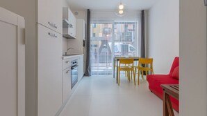 A modern kitchen with a dining area, a red sofa, and a view through a glass door. - GuestHost - Academy of Fine Arts -Modern Apt. with balcony! (Bologna)
