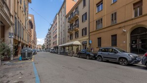 A street with parked cars, buildings with balconies, and a clear sky. - GuestHost - Academy of Fine Arts -Modern Apt. with balcony! (Bologna)