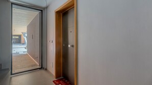 A hallway with a wooden door, a glass door leading outside, and a red welcome mat. - GuestHost - Academy of Fine Arts -Modern Apt. with balcony! (Bologna)