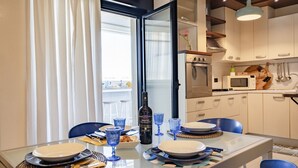 Et spiseområde med et glasbord, blå stole og en flaske vin.