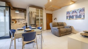 Et moderne køkken med indbygget køleskab, spisebord med stole og et opholdsområde med sofa.