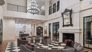 A spacious living area with a checkered floor, grey sofas, and a fireplace.