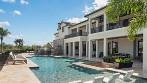 A large outdoor swimming pool with lounge chairs and a multi-level building with balconies.