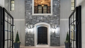 A grand entrance with a stone facade, a black door, and a small window above the door.