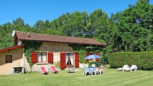 A rustic house with a red-tiled roof, a small garden with a table and chairs, and a hedge in the background. - Stunning private villa for 6 guests with WIFI, TV and pets allowed (Le Porge)