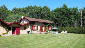 A two-story house with a red roof and a small garden area with a table and chairs. - Stunning private villa for 6 guests with WIFI, TV and pets allowed (Le Porge)