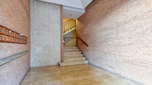 Un escalier avec une rampe en bois et un mur orné d’un motif sur un des côtés.