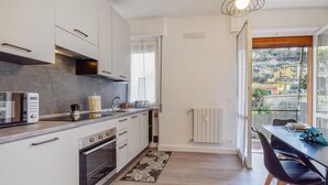 Une cuisine moderne avec des armoires blanches, un four encastré et une grande fenêtre.