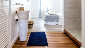 A modern bathroom with a large white sink, a mirror, and a shower area.