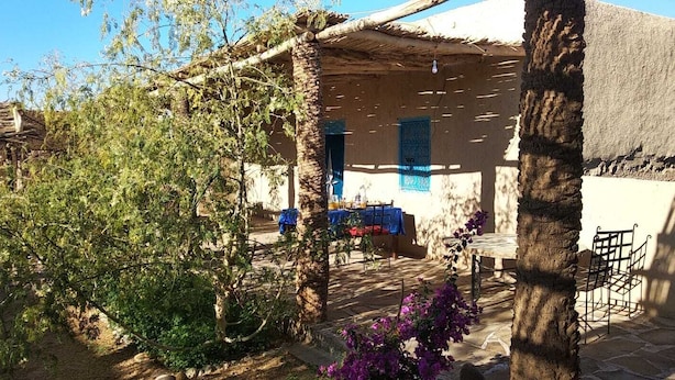Un edificio tradicional con techo de paja, un área de estar al aire libre techada y un camino de piedra.