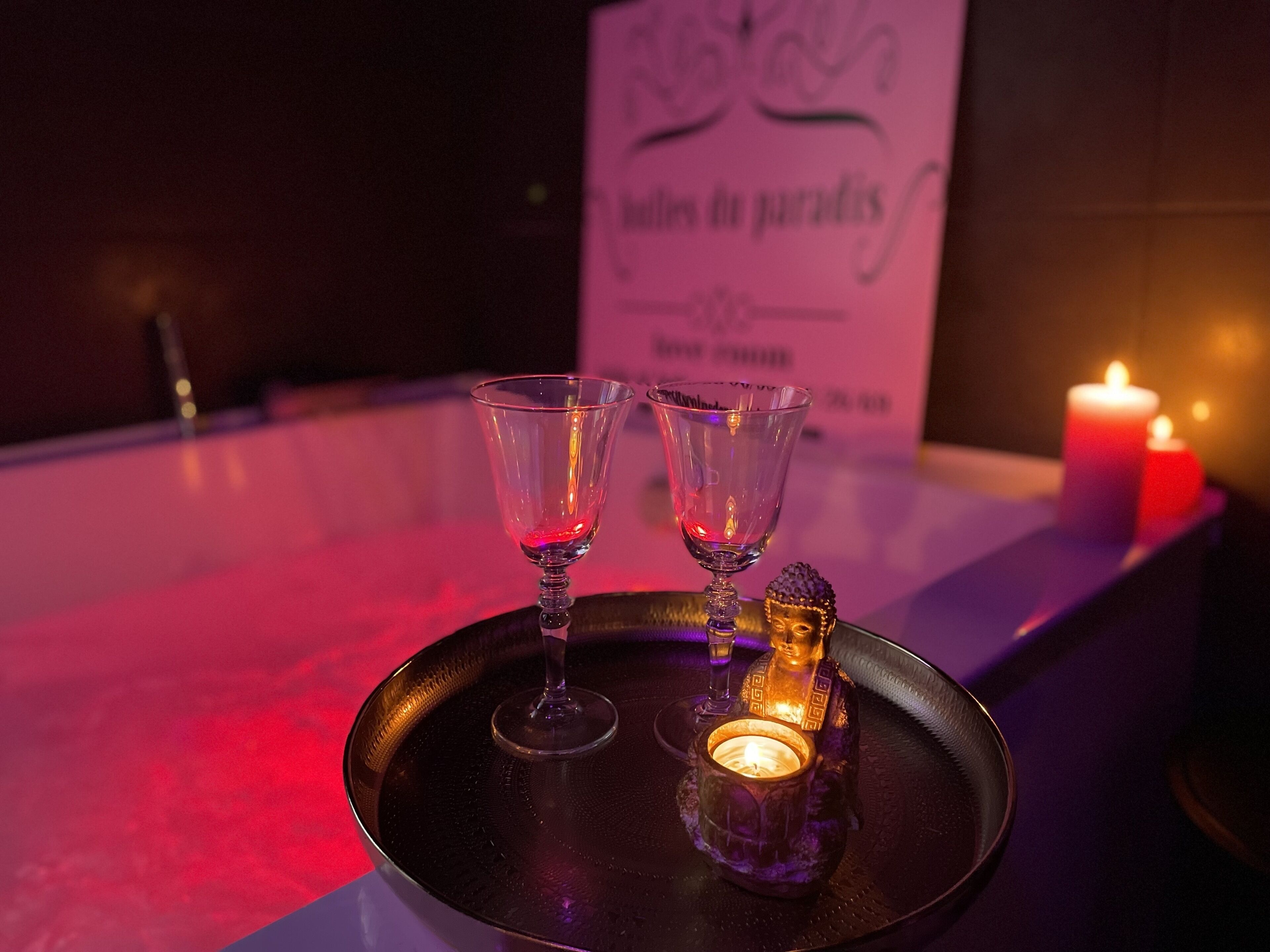 A tray with two glasses and a candle on a table, with a sign in the background.
