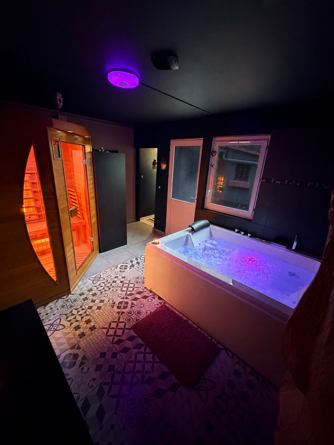 Un baño moderno con jacuzzi, sauna y zona de ducha con mampara de vidrio.