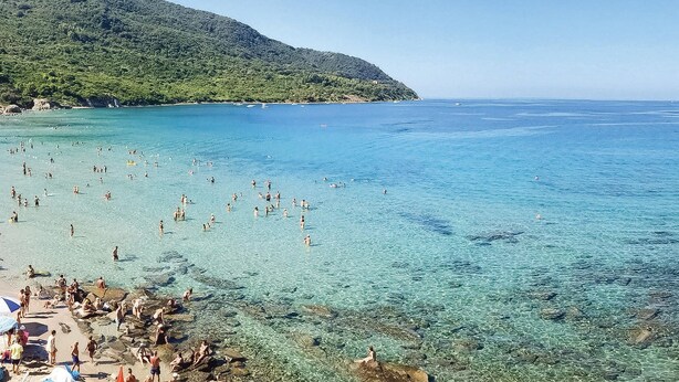 A beach with clear water, rocky shore, and a mountain in the background. - 2 bedroom stunning apartment in Ogliastro Marina (Ogliastro Marina)