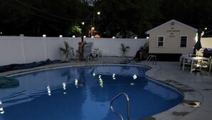 A swimming pool with a metal ladder, a white building labeled "NO. 1 LIFE SHACK," and a white fence. - The Weekender Unit #1 (Geneva-on-the-Lake)