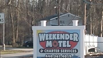 A sign for Weekender Motel advertising charter services and a contact number.