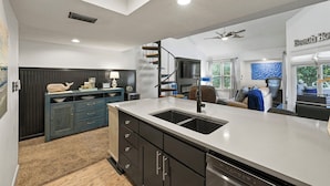 A modern kitchen with a central island, dark cabinetry, and a built-in stove.