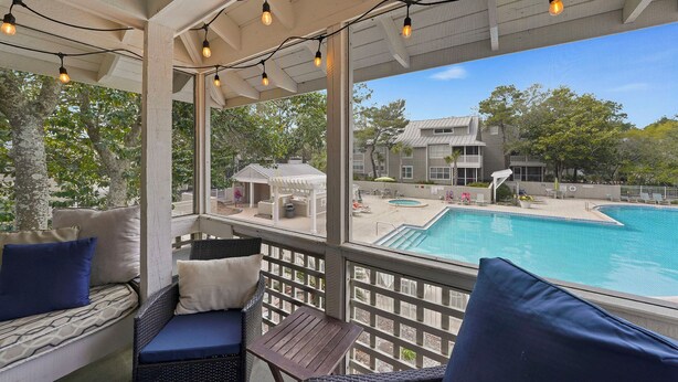 A covered outdoor area with a pool, seating, and string lights.