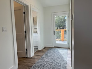 A hallway with a wooden floor, white walls, and a glass door leading outside. - Ruidoso Mountain Retreat w/ Hot Tub & Scenic Views (Ruidoso)