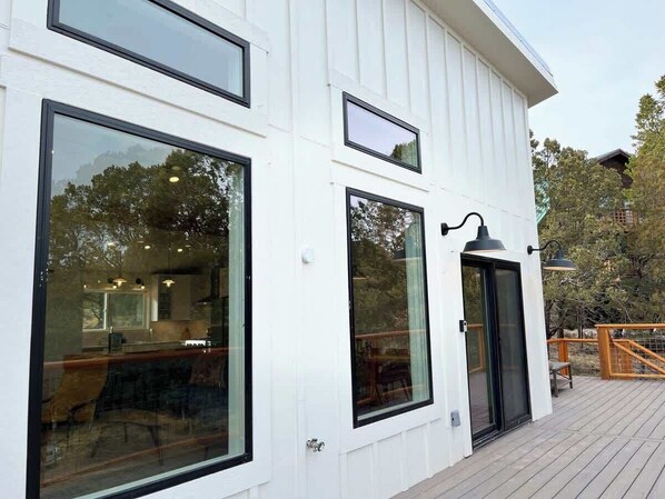 A white building with large windows, a deck, and a door.