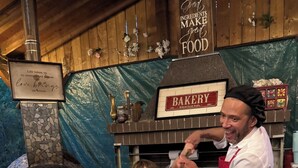 A bakery with a rustic interior, a pizza oven, and a person serving pizza. - Luxury Winter Gateaway (Nestleton Station)