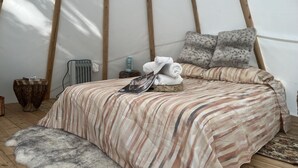 A cozy room with a bed, pillows, a small table, and a radiator. - Luxury Winter Gateaway (Nestleton Station)