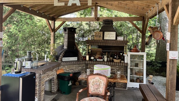 An outdoor kitchen area with a wood-burning stove, a welcome sign, and various cooking utensils. - Luxury Winter Gateaway (Nestleton Station)