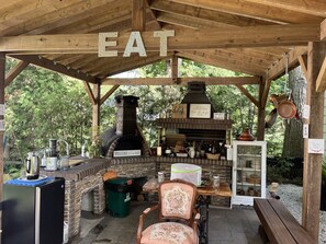 An outdoor kitchen area with a wood-burning stove, a welcome sign, and various cooking utensils. - Luxury Winter Gateaway (Nestleton Station)