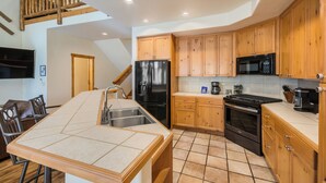 A kitchen with wooden cabinets, a refrigerator, a microwave, an oven, and a dining area with a table and chairs.