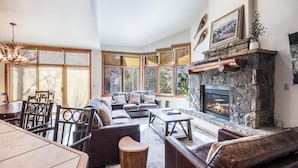 A cozy living room with a stone fireplace, leather sofas, and a dining area with wooden chairs and a table.