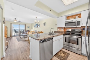 A modern kitchen with stainless steel appliances, a dishwasher, and a large island. - Four Winds 402 (Orange Beach)