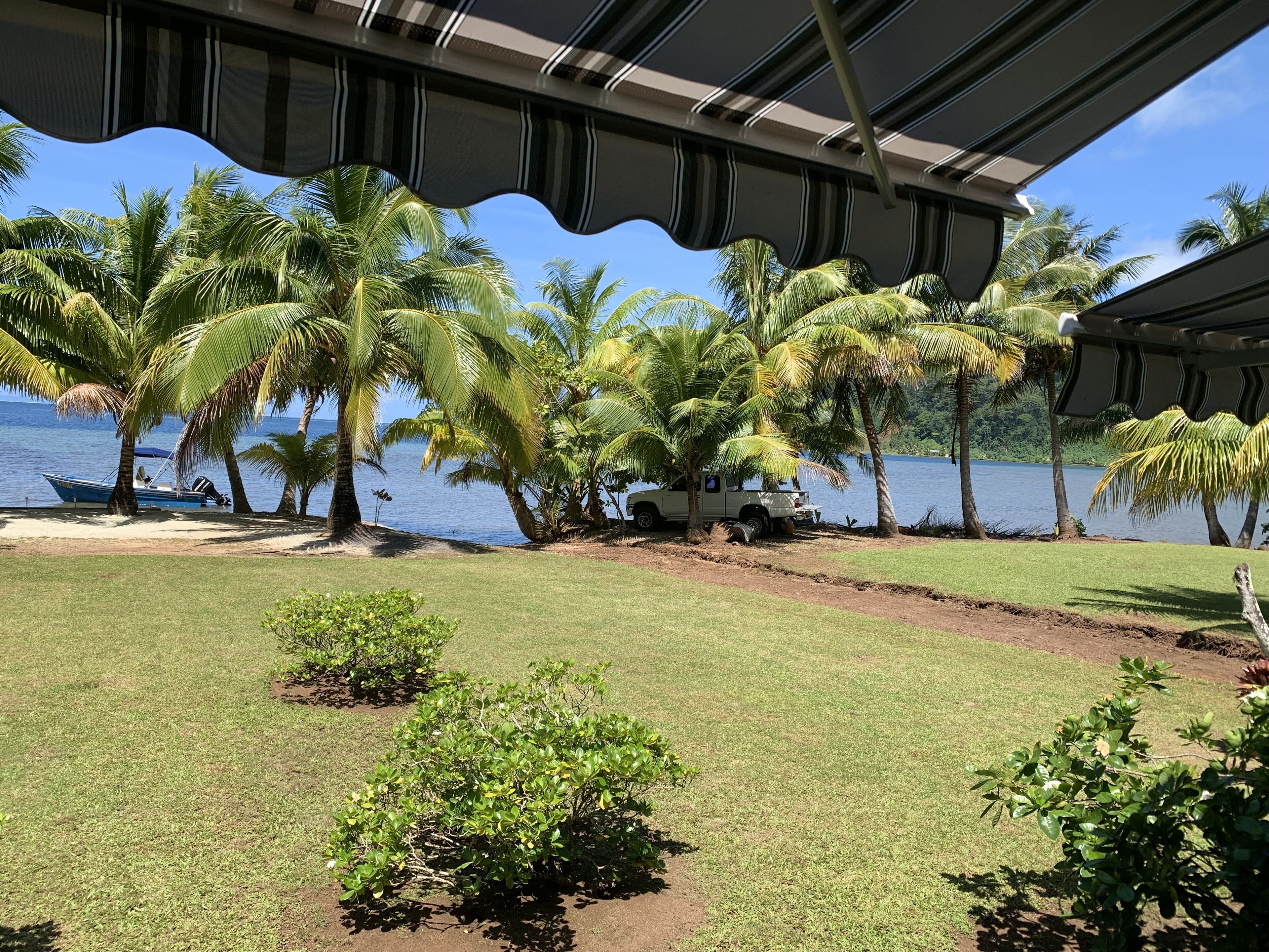 A covered outdoor area with a view of a lake and palm trees.