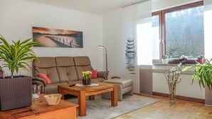 Ein modernes Wohnzimmer mit einer Couch, einem Couchtisch und einem Gemälde, das einen Sonnenuntergang über dem Wasser zeigt.