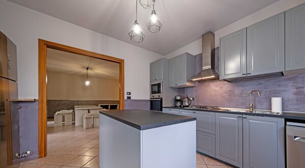 A modern kitchen with grey cabinets, a central island, and a built-in oven. - Villa i Roccoli - olive trees with private pool (Bardolino)