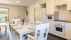 Una cocina moderna con armarios blancos, una mesa de comedor lista para cuatro personas y vistas al exterior.