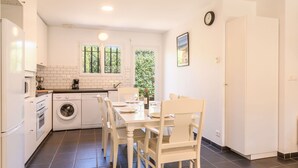 Una cocina compacta con comedor, que incluye lavadora, horno y una mesa con sillas.