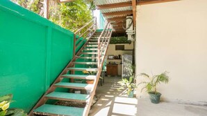 A staircase leading to a covered area with a green wall and potted plants. - ¡Acogedora habitación privada en el corazón de Quepos! (Quepos)