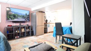 A compact living space with a kitchenette, a dining area, and a TV mounted on the wall.