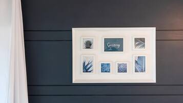 Une œuvre d’art encadrée, ornée d’imprimés botaniques, est accrochée à un mur en bois foncé.