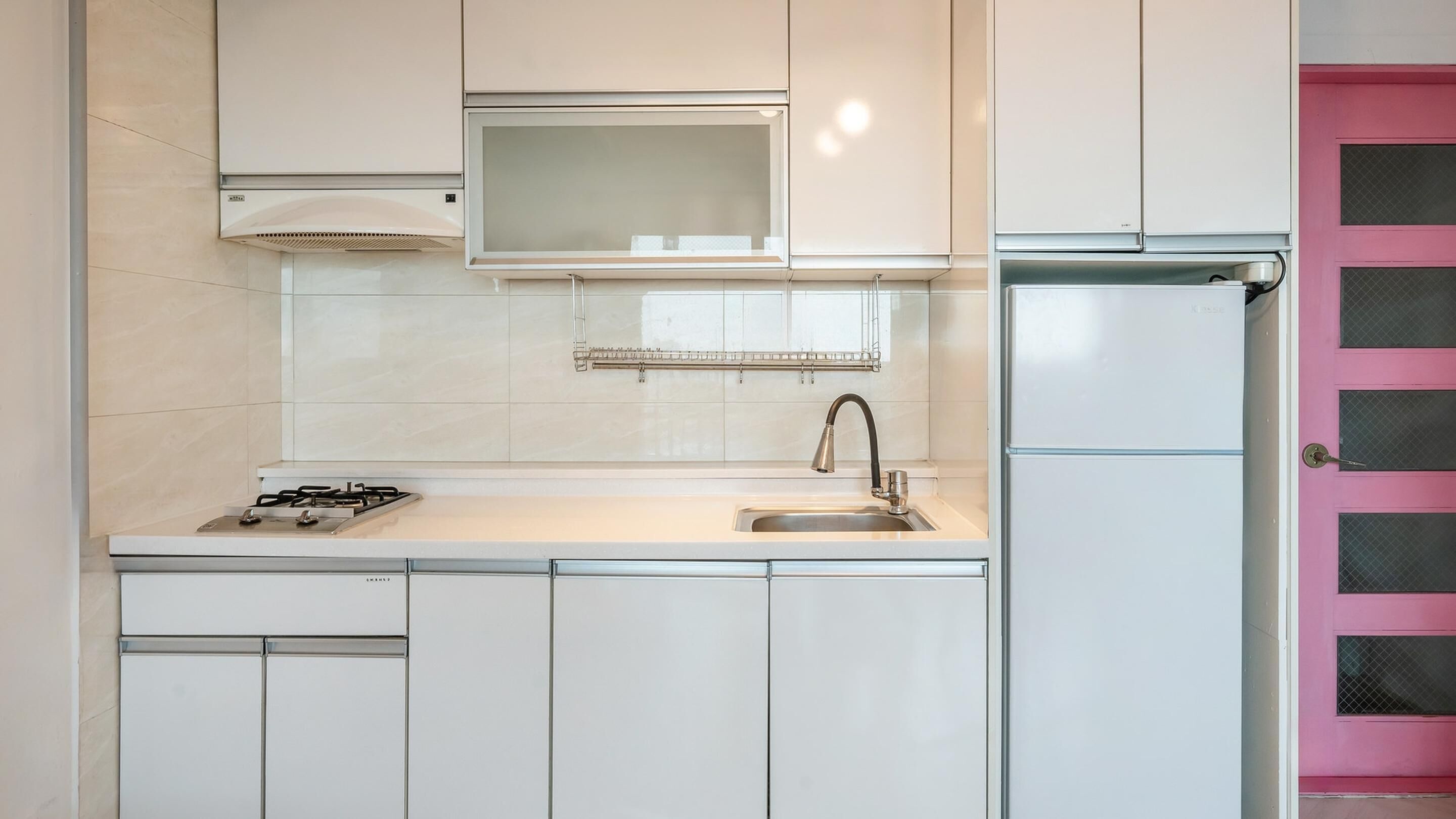 A kitchen with white cabinets, a stainless steel sink, a gas stove, a microwave, and a refrigerator.
