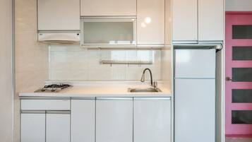 A kitchen with white cabinets, a stainless steel sink, a gas stove, a microwave, and a refrigerator.