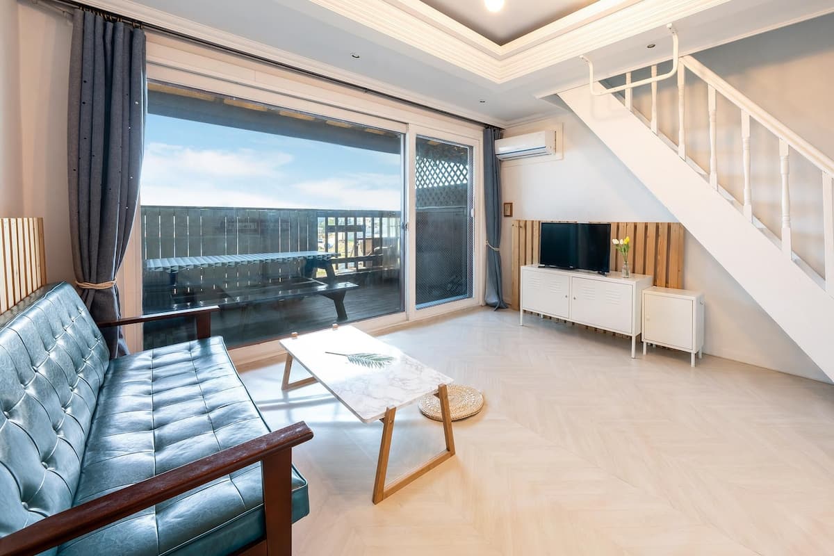 A modern living room with a sofa, a coffee table, a TV, and a staircase.